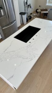 A new white granite countertop being installed on a kitchen island by Victor's Granite Counter-Tops in Millcreek, UT.