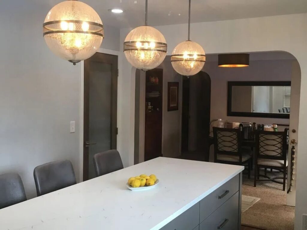 A kitchen island with modern pendant lights, leading to a dining area, completed by Myers & Myers Construction in Spokane, WA.