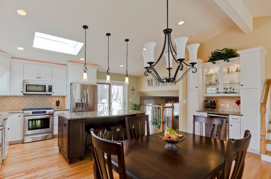 A bright kitchen remodel featuring white cabinets, a large island, and an adjacent dining area by Synergy Builders in West Chicago, IL.