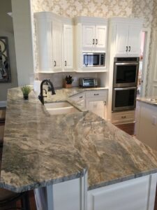 A kitchen island with a beautiful granite countertop and white cabinetry installed by Home Platinum Services, LLC in Plano, TX