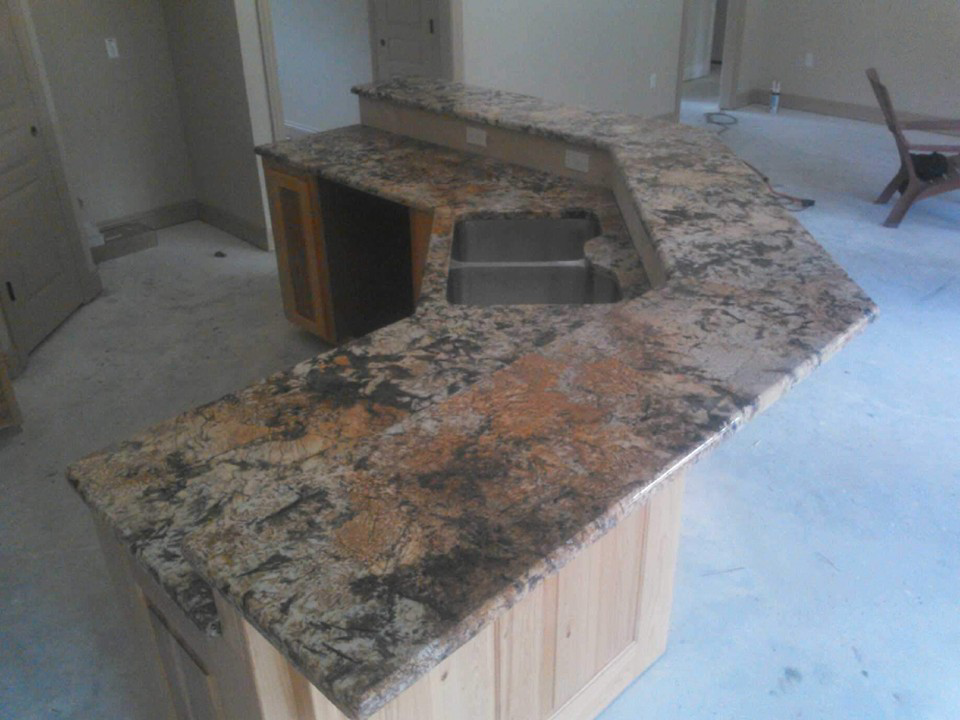 A spacious kitchen island featuring multi-toned granite countertops and a double sink installed by Alfortish Marble & Granite, LLC in Baton Rouge, LA.