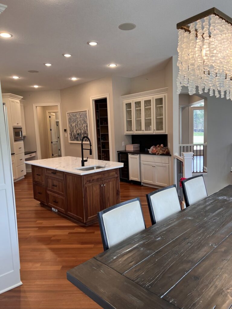 A spacious kitchen featuring a large island with a sink, dark wood cabinets, and light countertops, installed by Inova Builds in Bloomington, MN.