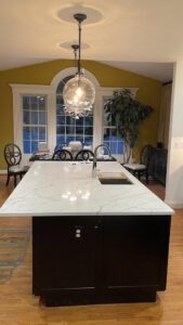 A kitchen with a newly installed large island, modern countertops, and a contemporary light fixture by Ruach Home Services in Laurel, MD.