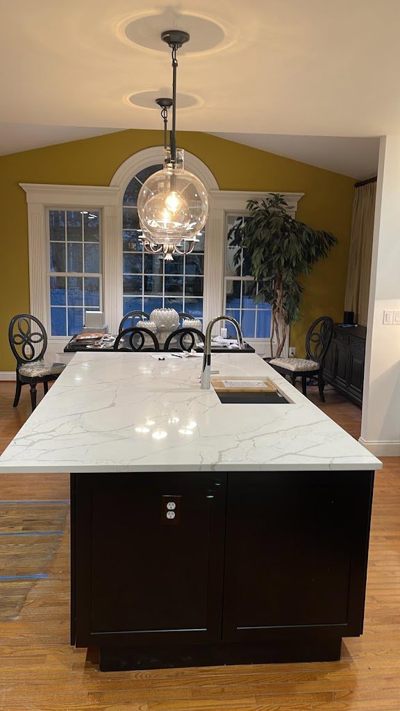 A kitchen with a newly installed large island, modern countertops, and a contemporary light fixture by Ruach Home Services in Laurel, MD.