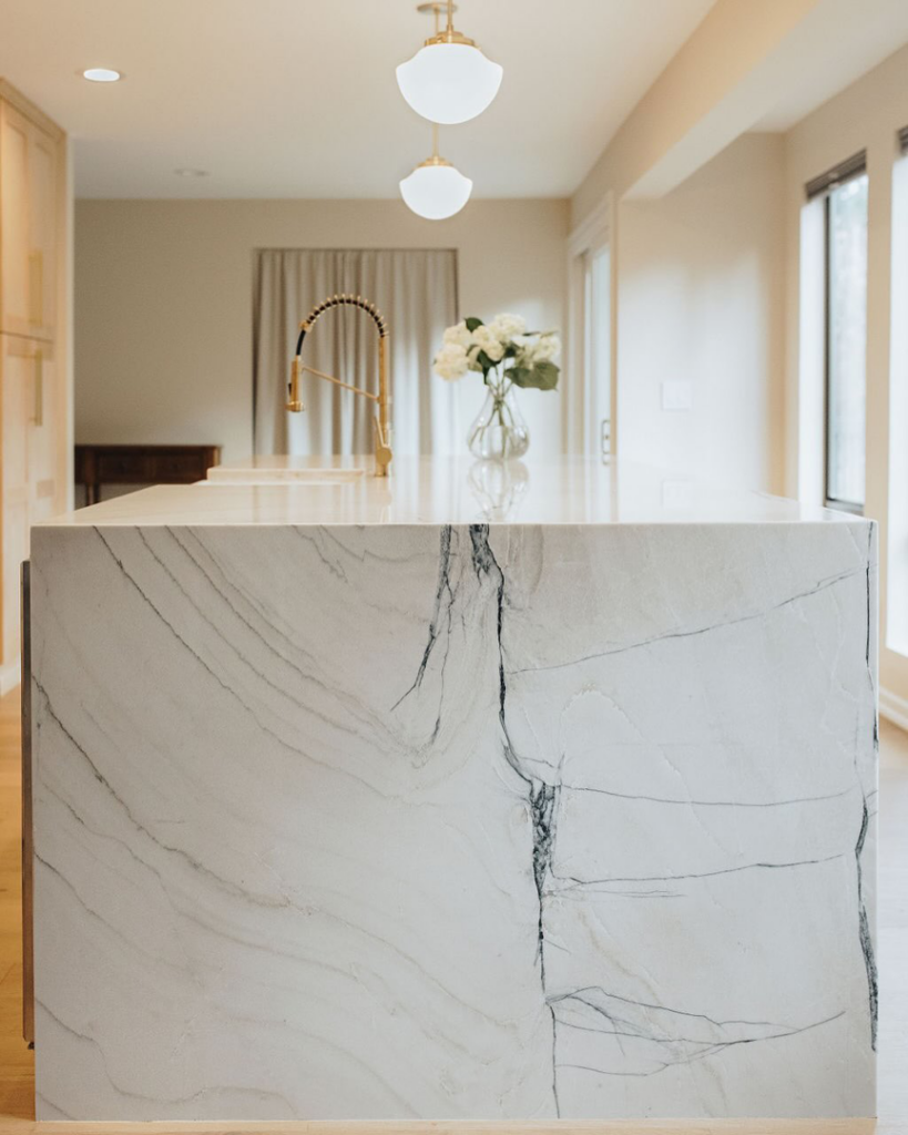 A stunning kitchen island with a veined white quartz countertop and gold faucet installed by Atlantic Tile & Granite in Kent, WA.