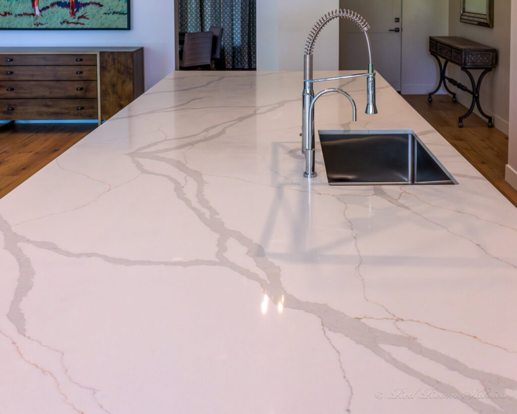A modern kitchen island with a stainless steel sink and pull-down faucet installed by Ignite Construction in Tempe, AZ.