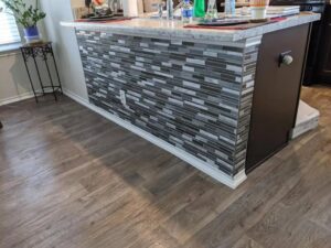 A kitchen island featuring a decorative tile facade and new flooring, a renovation detail by Morin Construction LLC in San Antonio, TX