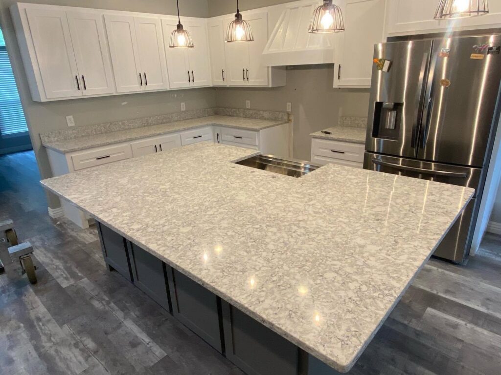A modern kitchen featuring a large island, white cabinets, and light speckled countertops installed by Javier's Countertops in Springdale, AR