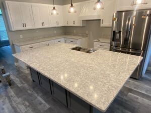 A modern kitchen featuring a large island, white cabinets, and light speckled countertops installed by Javier's Countertops in Springdale, AR