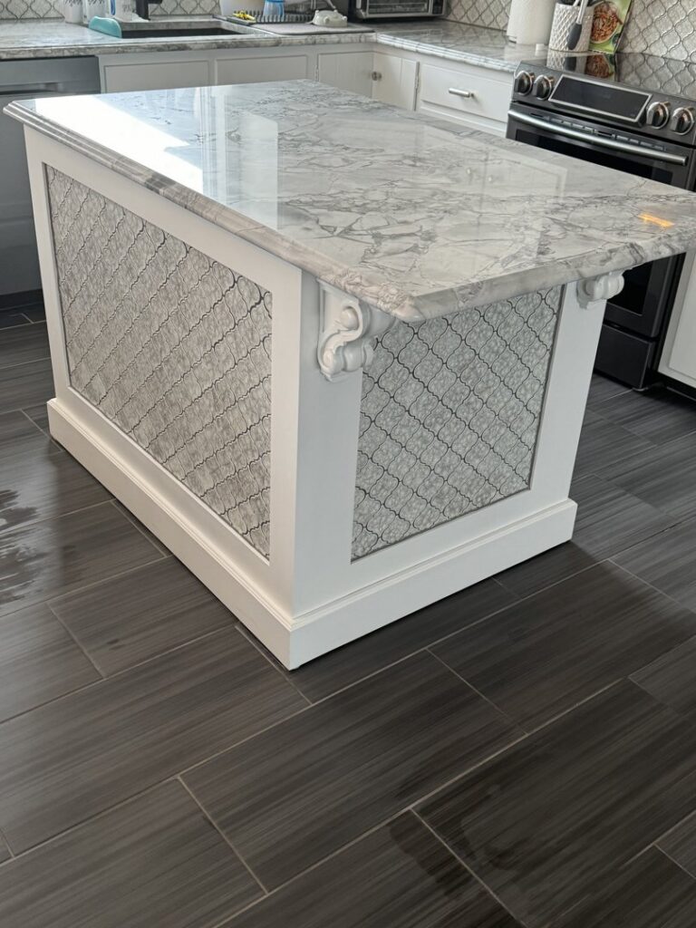 A kitchen island featuring decorative tile panels and dark floor tiles, expertly installed by Tile Jawn in Philadelphia, PA.