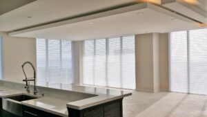 A spacious kitchen and living area featuring a large island, modern ceiling design with recessed lighting, and expansive windows, remodeled by JNY Remodeling INC in Fort Lauderdale, FL.
