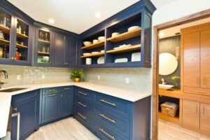 A kitchen and pantry area featuring blue cabinets and open shelving by Kornerstone Kitchens in Orlando, FL.