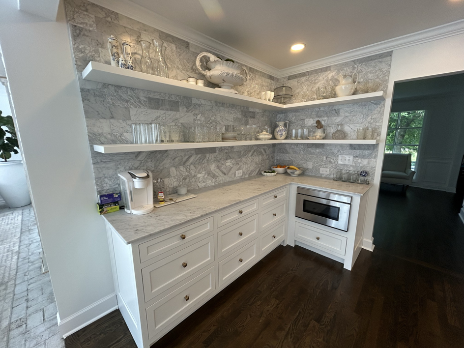 A well-organized kitchen pantry with white cabinets, floating shelves, and a marble backsplash, installed by Safe Haven Home Services in Nashville, TN.