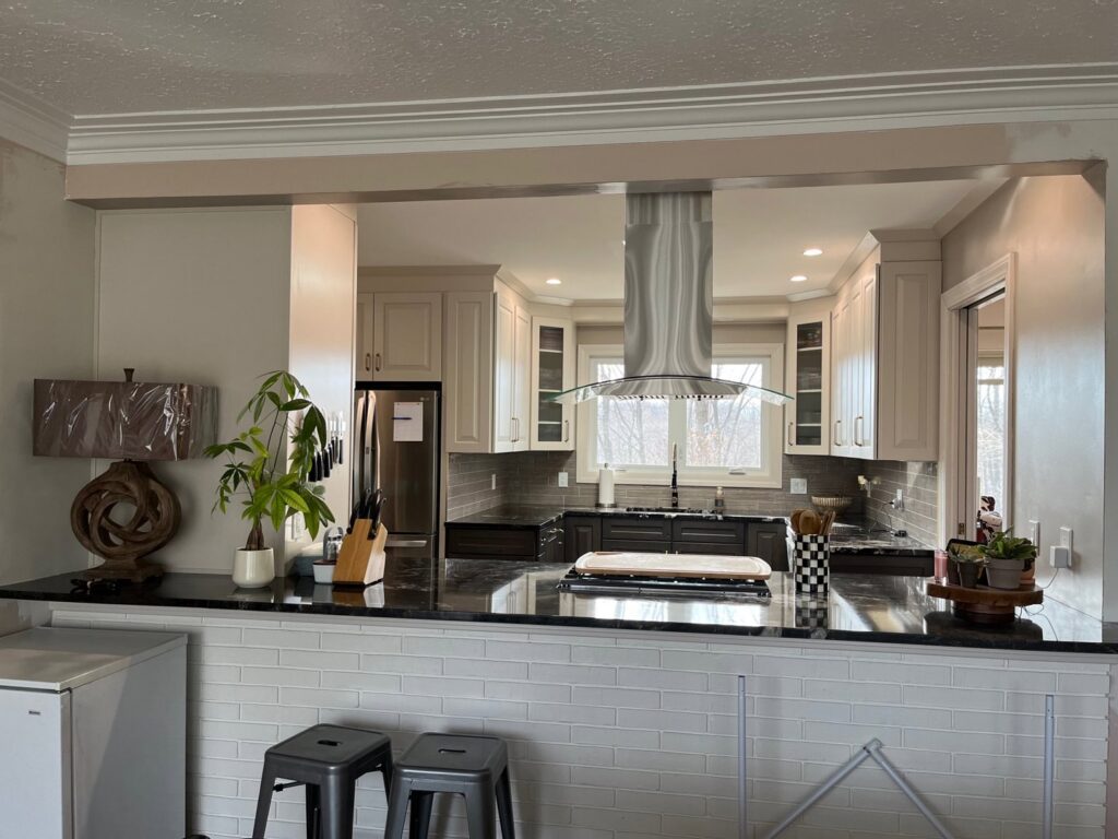 A remodeled kitchen with a pass-through window, light cabinets, and dark countertops completed by CLE Remodeling Co in Cleveland, OH.