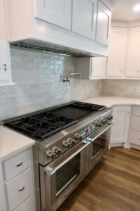 Close-up of a professional kitchen range and tiled backsplash installed by Holaway Custom Builds in Fayetteville, AR.