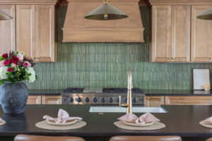 Close-up of a kitchen range, green tile backsplash, and gold faucet installed by HomePro Improvements, Roswell, GA.