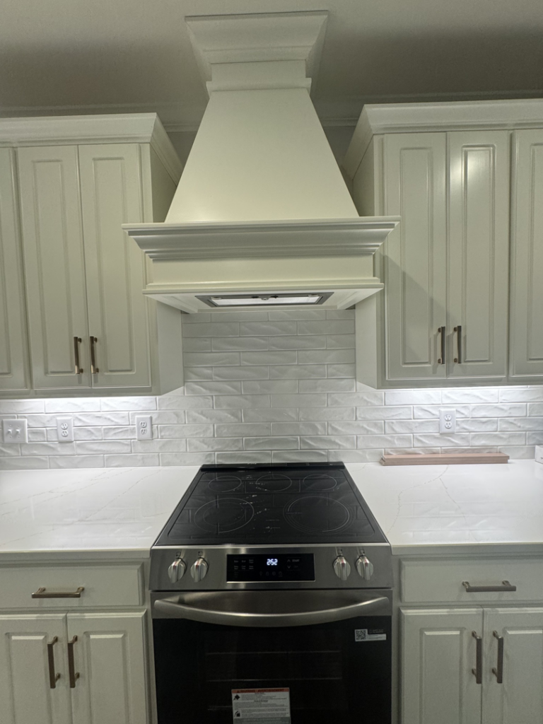 Kitchen with a newly installed range hood and subway tile backsplash by Adamson Construction Group in Salem, AL.