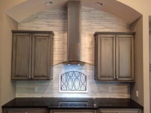 A kitchen remodel featuring a stylish range hood, custom cabinets, and decorative tile backsplash by Pro Remodel LLC in St. Charles, MO.