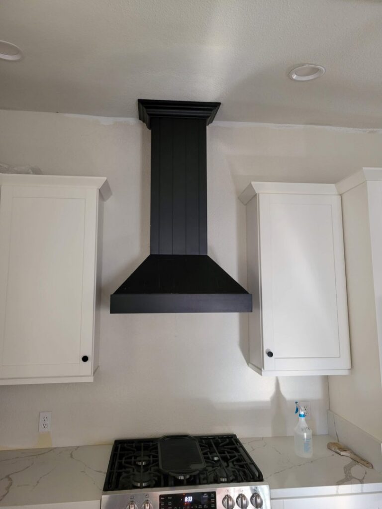 A new black kitchen range hood professionally installed above a stove by McCarran Handyman Services in Boulder City, NV.