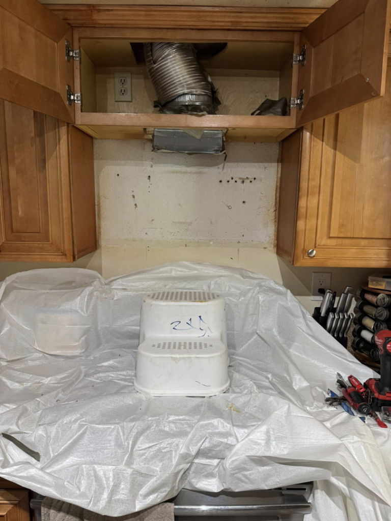 Kitchen area with a range hood removed, showing exposed ductwork and electrical outlets during a remodel by Peraza Handyman Services Llc in Bakersfield, CA.