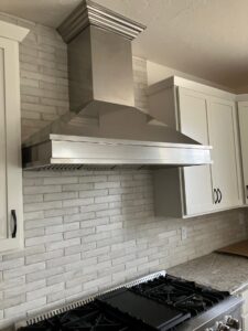 A newly installed range hood above a stove with a white subway tile backsplash, a kitchen renovation by DCM Multi Service llc in Harrisburg, PA.