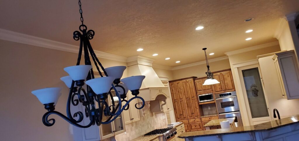 A renovated kitchen featuring new recessed lighting and a decorative chandelier by Constructed by 360 LLC in Meridian, ID.