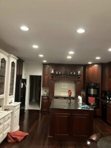 A renovated kitchen featuring dark wood cabinets, a central island, and new recessed lighting by DCM Multi Service llc in Harrisburg, PA.