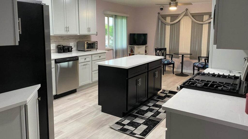 A renovated kitchen featuring black island cabinets, white wall cabinets, and new flooring installed by CLE Remodeling Co in Cleveland, OH.