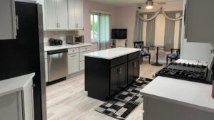 A renovated kitchen featuring black island cabinets, white wall cabinets, and new flooring installed by CLE Remodeling Co in Cleveland, OH.