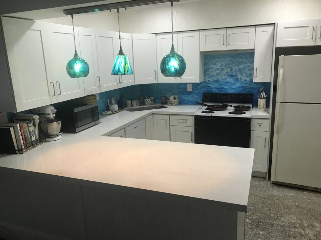 A completed kitchen remodel featuring white cabinets and a vibrant blue backsplash by BRM Construction in Miami, FL.