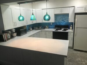 A completed kitchen remodel featuring white cabinets and a vibrant blue backsplash by BRM Construction in Miami, FL.