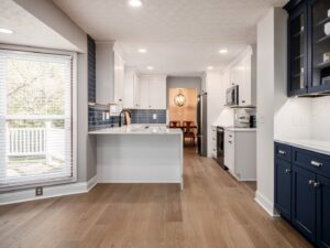 A renovated kitchen featuring white and dark blue cabinets with a blue subway tile backsplash by Desert Remodel in Scottsdale, AZ.