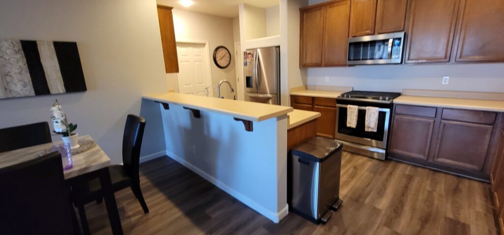 A kitchen remodel featuring a breakfast bar, stainless steel appliances, and wood-look flooring by LJ Builders in Chandler, AZ