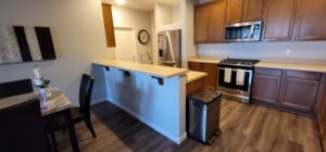 A kitchen remodel featuring a breakfast bar, stainless steel appliances, and wood-look flooring by LJ Builders in Chandler, AZ