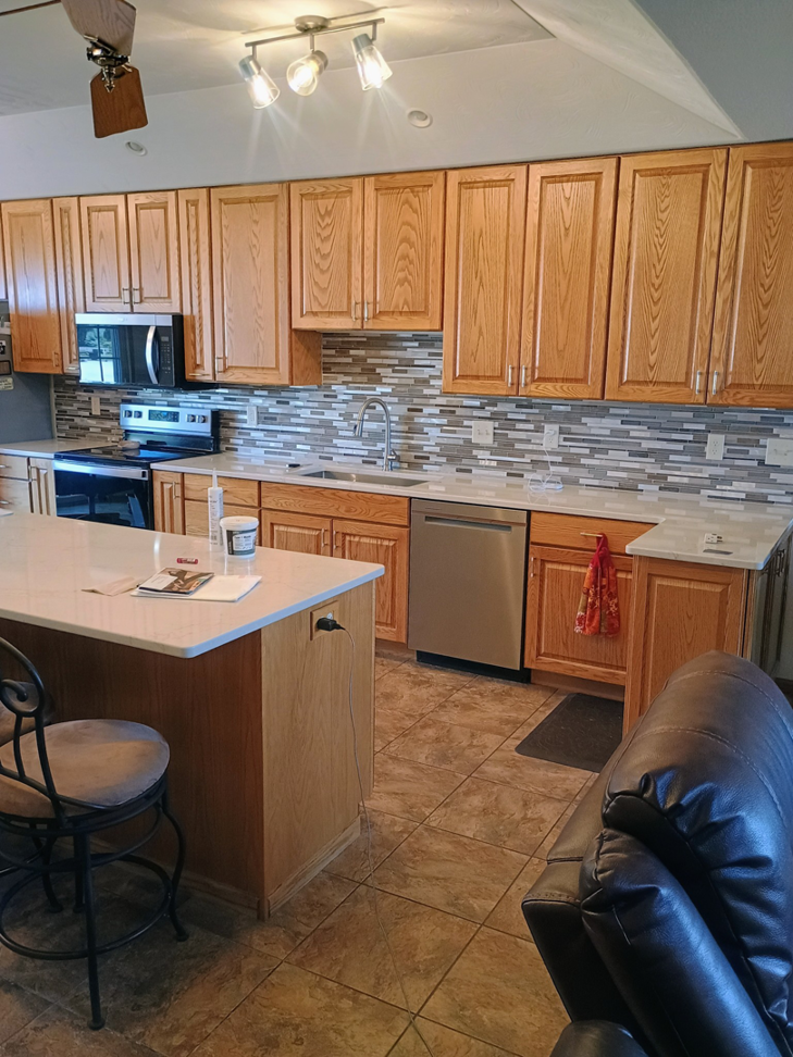 A complete kitchen remodel featuring new wooden cabinets and tiled backsplash by The Cowboy Carpenter Handyman Service LLC in Bismarck, ND.
