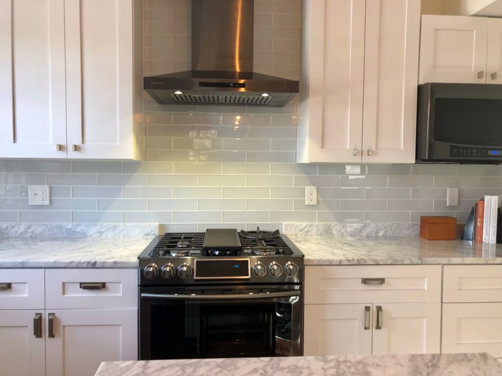 A modern kitchen remodel with white cabinets, subway tile backsplash, and stainless steel appliances by Fine Line Construction and Remodeling in St. Charles, MO.