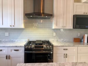 A modern kitchen remodel with white cabinets, subway tile backsplash, and stainless steel appliances by Fine Line Construction and Remodeling in St. Charles, MO.