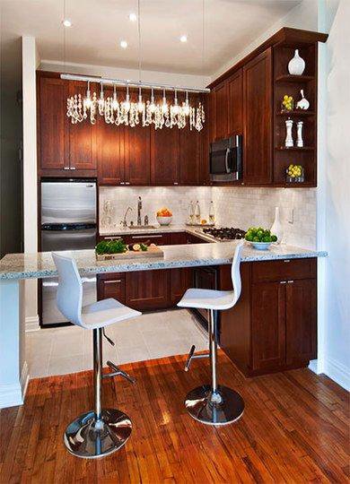 A kitchen remodel featuring dark wood cabinets, a small island, and a chandelier by Chicago Service Source Inc in Chicago, IL