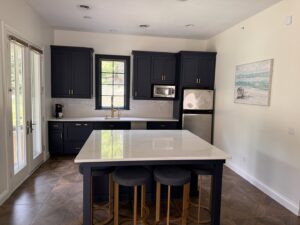 A stylish kitchen remodel with dark blue cabinets, a large white island, and stainless steel appliances by Inova Builds in Bloomington, MN.