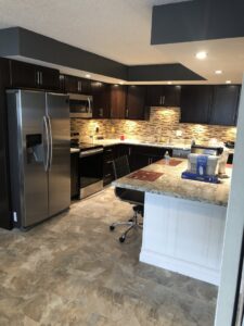 Modern kitchen remodel with dark wood cabinets and stainless steel appliances by Segovia LLC interiors in Madison, WI.