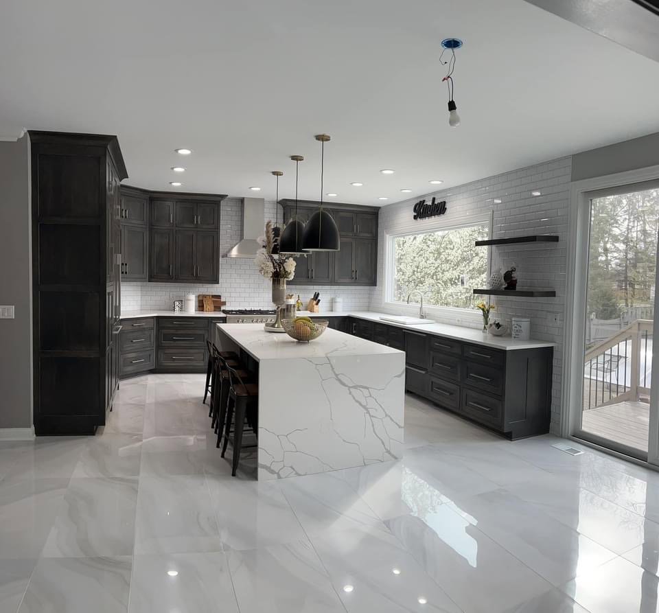 A kitchen remodel featuring dark cabinets, white subway tile, and a large white island by J and R Granite Industry in Columbus, OH.