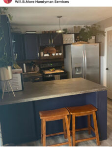 A completed kitchen remodel with dark blue cabinets, a wooden backsplash, and a dark countertop by Will.B.More Handyman & Remodel in West Jordan, UT