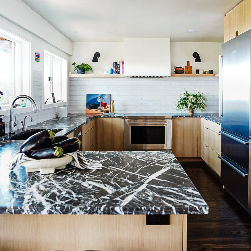 A complete kitchen remodel featuring dark marble-look countertops and white subway tile backsplash by Atlantic Tile & Granite in Kent, WA.