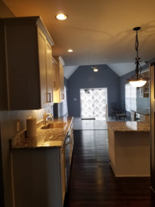 A long view of a renovated kitchen with dark wood floors and recessed lighting by Land Bank Builders and Associates in Gary, IN