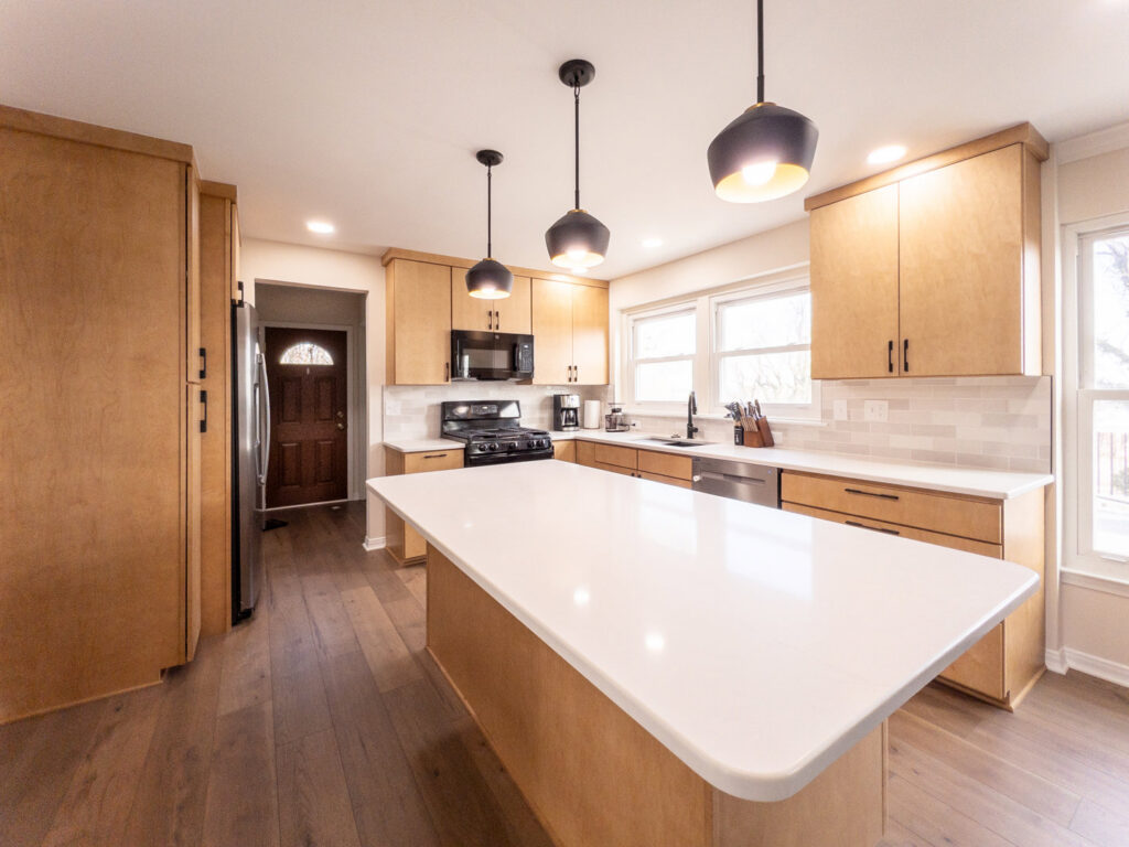 A modern kitchen remodel with light wood cabinets and a large white island by Dream Design Build & Remodeling, Inc. in Baltimore, MD