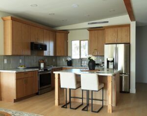 A newly remodeled kitchen with light wood cabinets, stainless steel appliances, and an island with seating by American Wolf Construction in Mesa, AZ