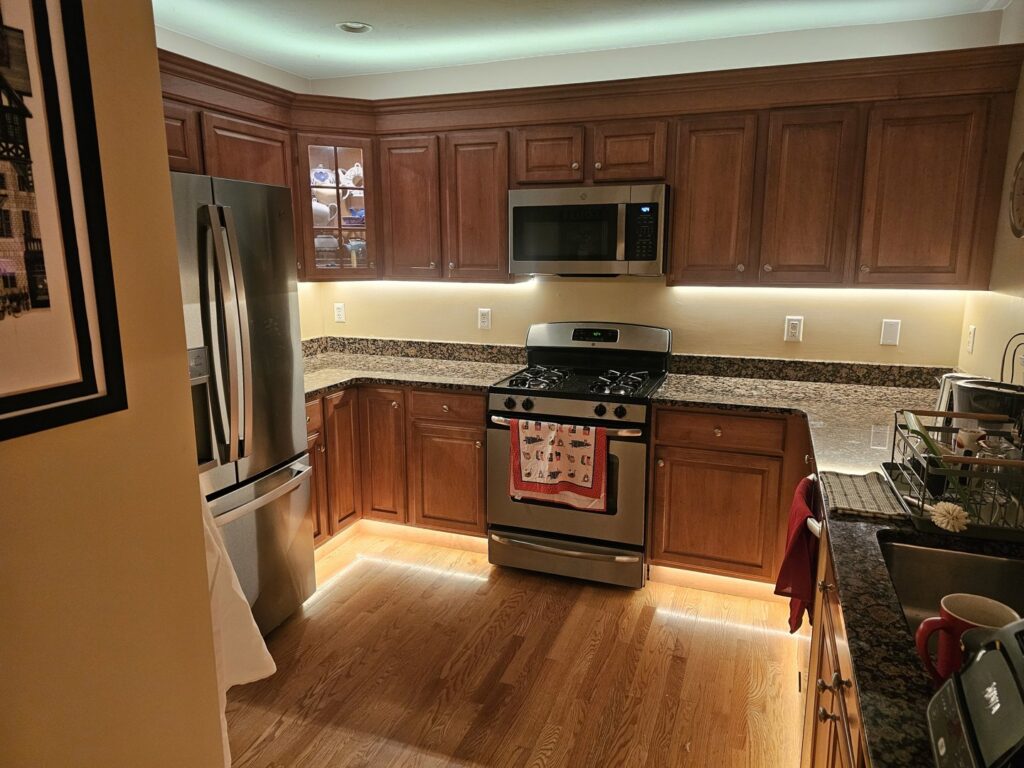 A newly remodeled kitchen featuring dark wood cabinets, granite countertops, and under-cabinet lighting by Modern Remodel Build & Design in Worcester, MA.