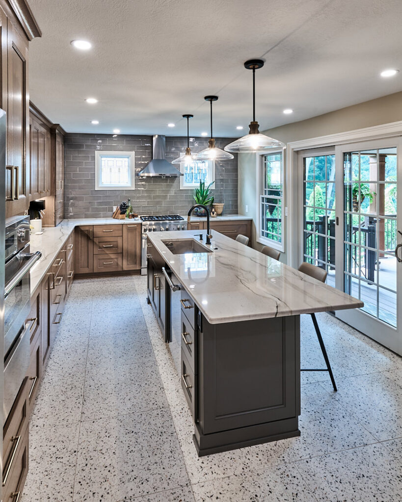 A kitchen remodel featuring a long island, wood-look cabinets, and grey subway tile backsplash by North Shore Kitchens in Pittsburgh, PA.