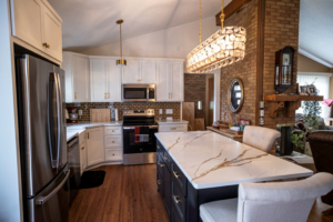 A newly remodeled kitchen featuring white cabinets, a dark island with a quartz countertop, and modern appliances by Satin Touch, Inc. in Ham Lake, MN.