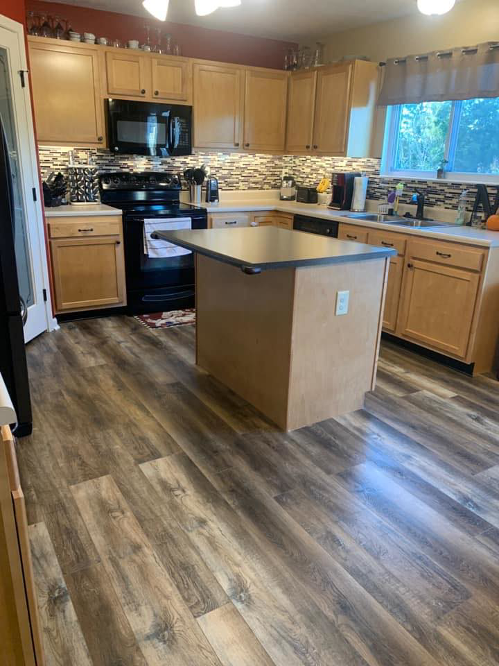 A renovated kitchen featuring new laminate flooring, a tiled backsplash, and updated cabinets by Berling Remodeling llc in Highland Heights, KY.